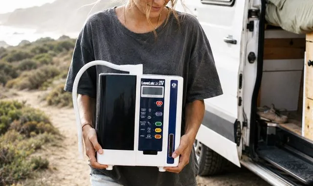 Un voyageur tenant le compact LeveLuk JR IV à côté d'un camping-car sur la côte